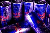 Close-up of multiple Red Bull cans with water droplets, highlighting freshness and energy.